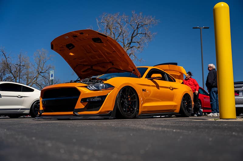 Orange Mustang with hood up at car show